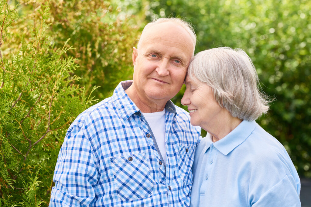 Portrait of loving senior couple embracing tenderly posing for camera in beautiful garden