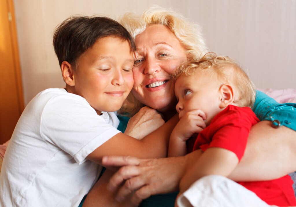 Happy grandmother hugging with her grandchildren at home