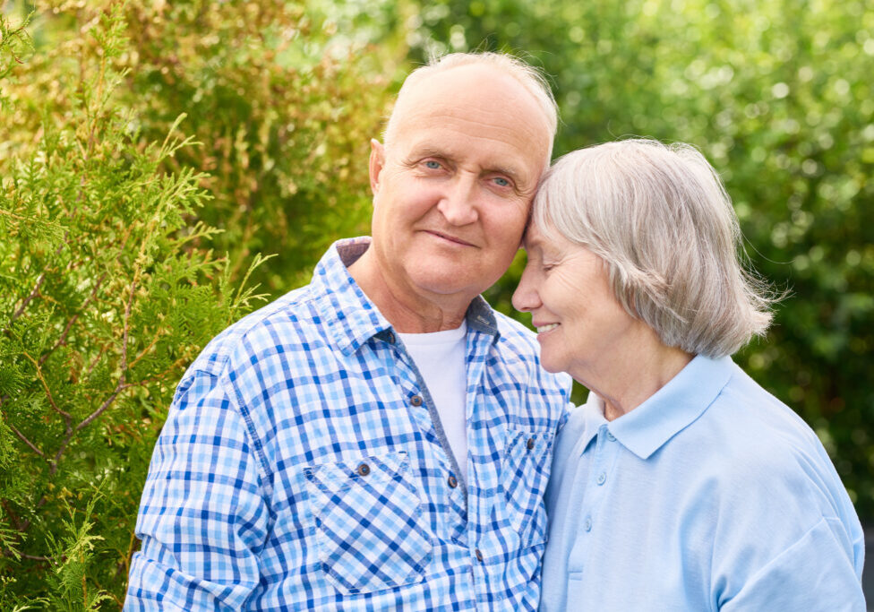 Portrait of loving senior couple embracing tenderly posing for camera in beautiful garden